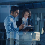 Two professionals collaborate on a tablet in a modern office setting