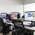 Modern office with multiple desks, computers, and ergonomic chairs