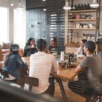 Group of people gathered around wooden table in cozy café setting