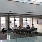 Modern glass-walled conference room with people meeting