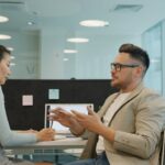 Two professionals discuss business ideas at a modern office table