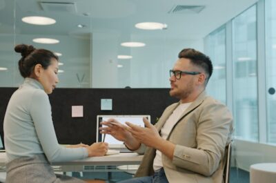 Two professionals discuss business ideas at a modern office table
